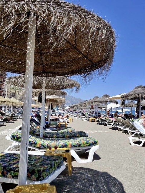 Sunbeds under straw parasols
