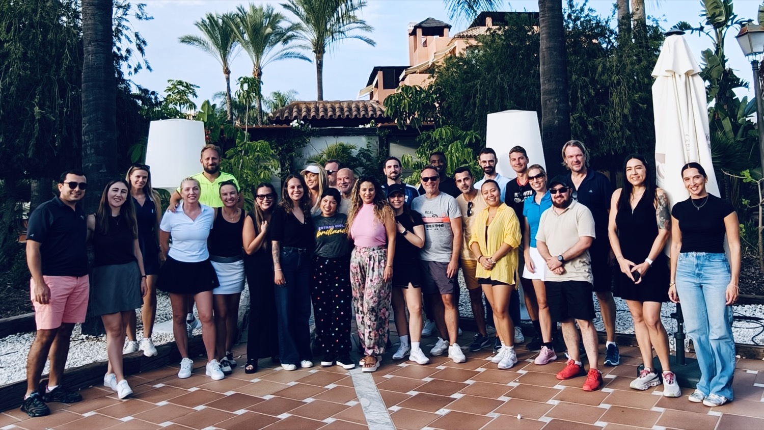 El grupo de la tarde de pádel de iGaming Circle, juntos en un patio con palmeras