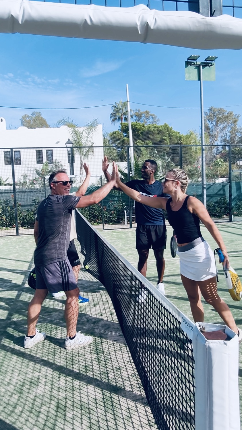 Jugadores chocando las manos por encima de la red en la pista de pádel